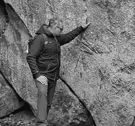 Thomas Lücke lehnt an einem großen Felsen im Wald
